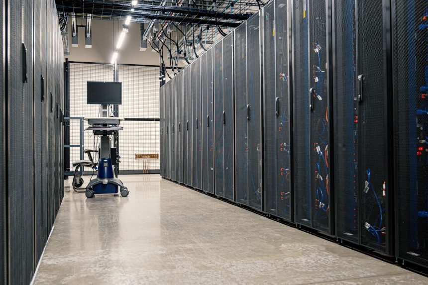 Armários metálicos com servidores, dispositivos de rede e cabos em um data center moderno.
