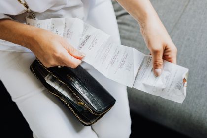 Mãos organizando vários recibos de compras retirados de uma carteira preta.