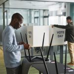 Homens preparam cabines de votação em uma seção eleitoral interna.