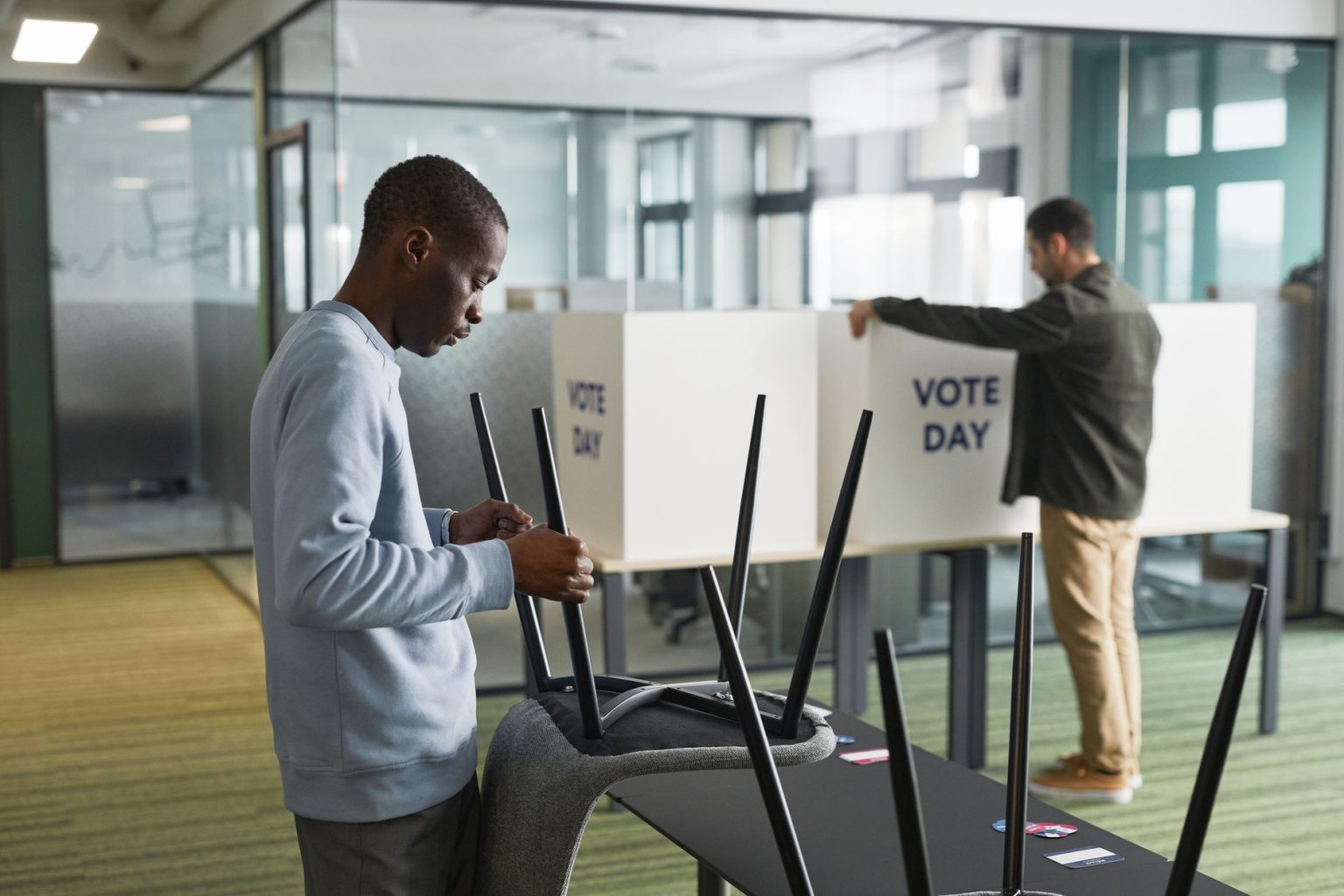 Homens preparam cabines de votação em uma seção eleitoral interna.